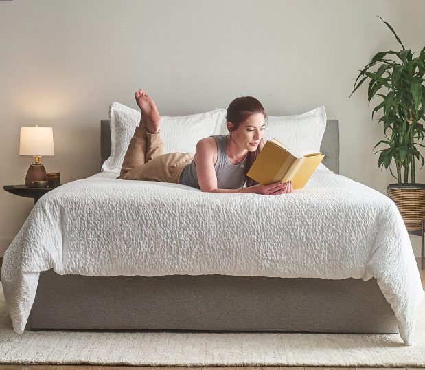 With our no iron top cover, your beds will be wrinkle free by design. Image shows a model reading a book on our Cumulus Top Cover.