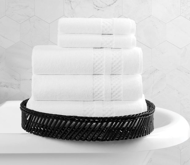 A stack of white Capital Collection bath towels shown in a basket on the edge of a towel. Because these are bath towels made in America, they once graced the white house.