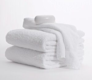 This image is a stack of Classic Dobby towels with a washcloth and a bar of fine milled soap on top.