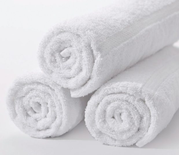 Set of three affordable cotton towels rolled and stacked on each other. The Classic Dobby is visible on the towel and is basically three rows of an arrow design.