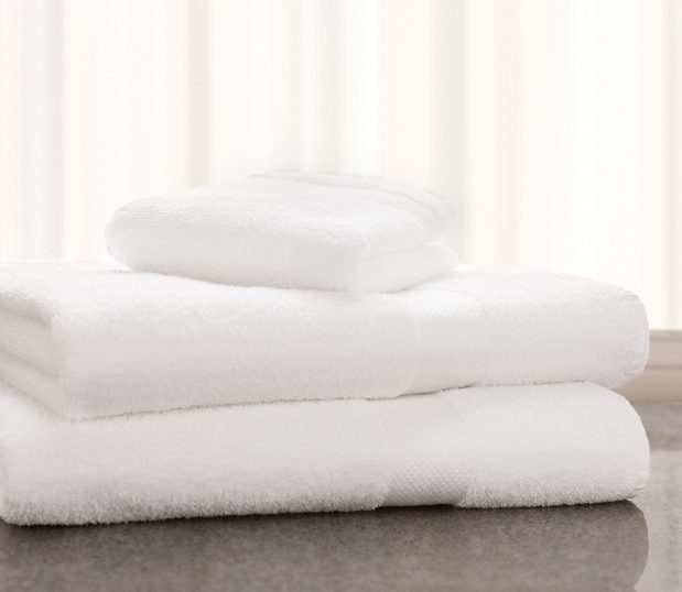 Image of two white long-lasting towels and a single wash towel are stack on a bathroom countertop.