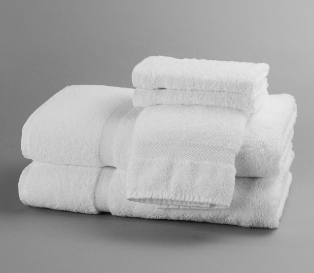 These white durable cotton towels towels, hand towel and two wash cloths are stacked and arranged in a way to show off the decorative dobby border.