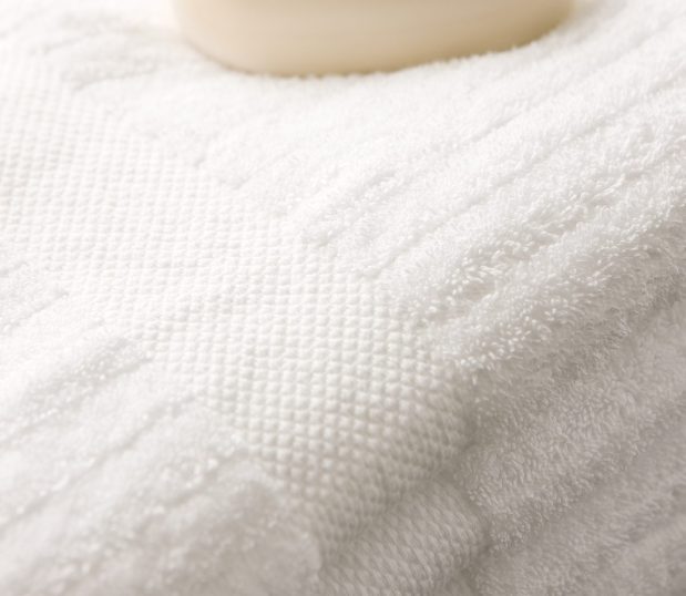 This image shows a detail of luxurious striped bath towels with a bar of soap in the background.