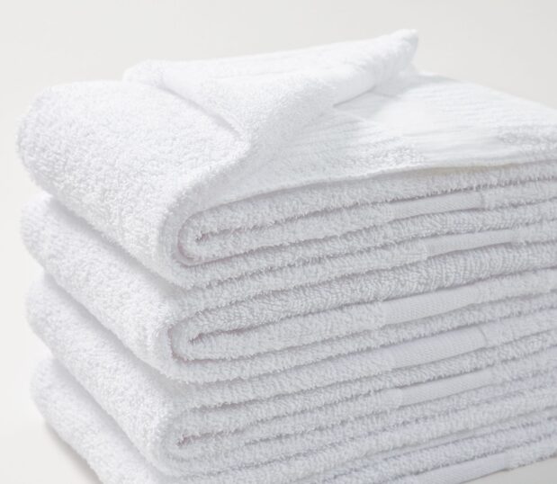 A stack of four folded PerVal® bath towels is shown here on a white background. The ribbed weave sides add strength at the portion of the towel that typically gets the most wear.