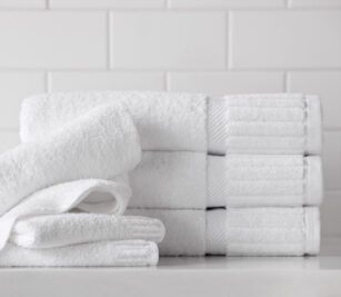 The Piano Key collection features 100% cotton hotel towels with an elegant dobby border. The sophisticated look is finished with distinctive piano key end panels. Image shows a decorative stack of piano key towels.