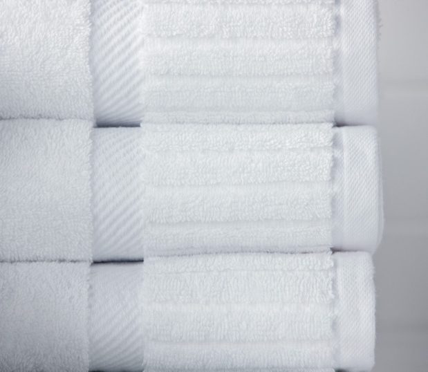 The Piano Key collection features 100% cotton hotel towels with an elegant dobby border. Image shows the decorative end panel of a piano key towel stack.