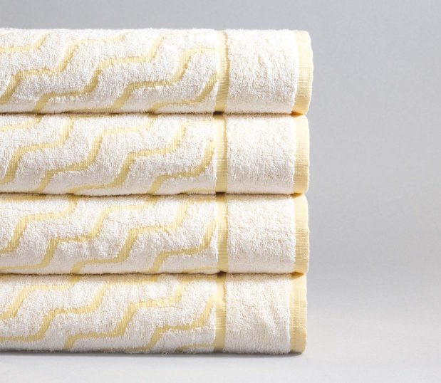 Four colorfilled pool towel shown in a stack. These luxury pool towels have the Wave Design with yellow weft.