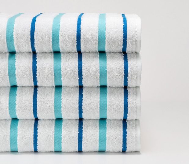 Set of four Seaglas striped pool towels. The towels have blue, and slightly wider teal stripes.