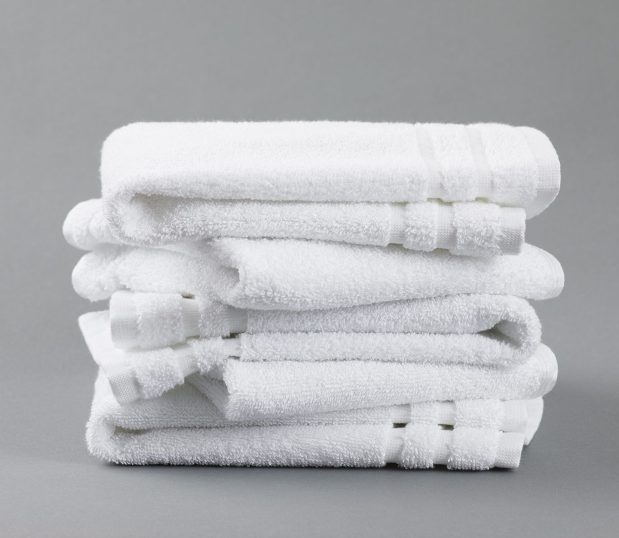 Image of the white VersaTowel with 4 stacked towels on a grey background.
