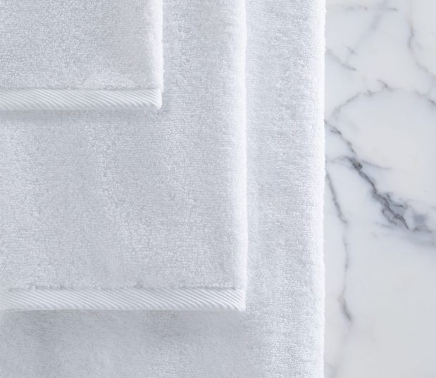 Quality towels shown hanging against a white marble wall.