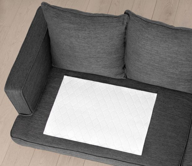 Our patented ComPly® Underpads feature tri-component fabric that wicks fluid away from the patient and traps the fluid in a super-absorbent all-cotton lower ply. Shown here: an overhead view of the Comply Underpad on a couch.
