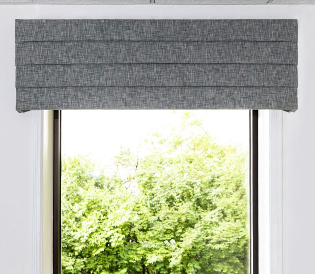 Seen in this photo is an image of a grey tweed fabric valance with horizontal quilting. Custom cornice and top treatments are available in a multitude of colors.