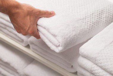 A hand grabs a towel from a stack of freshly laundered linens.