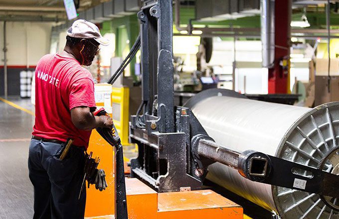 Man wearing red shirt working in a textile manufacturing facility