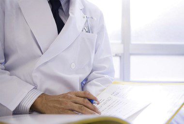 Doctor in a lab coat looking over paperwork.