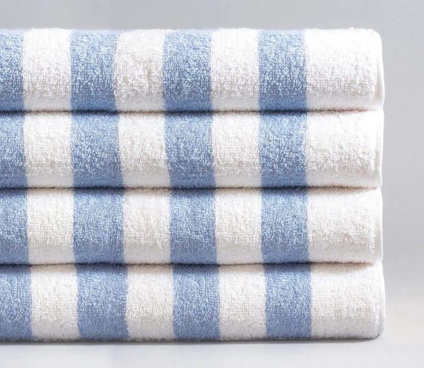 A stack of blue cabana striped pool towels on grey background.