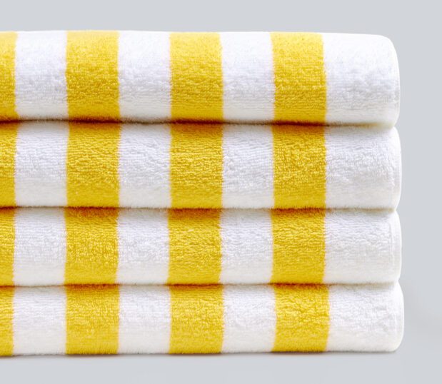 A stack of yellow cabana striped pool towels on grey background.