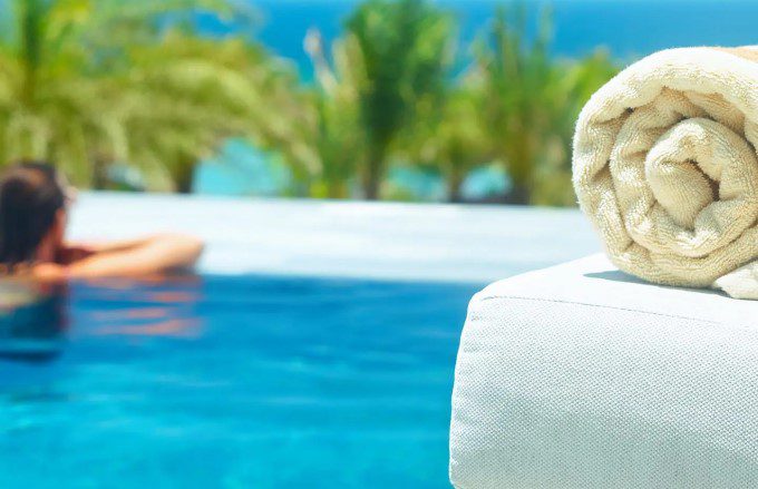 a hotel guest relaxing in a swimming pool with palm trees in the background.